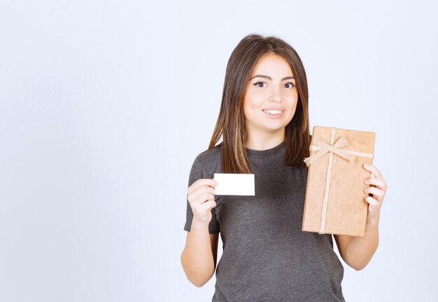 Photo de jeune femme souriante tenant une boîte-cadeau avec carte.