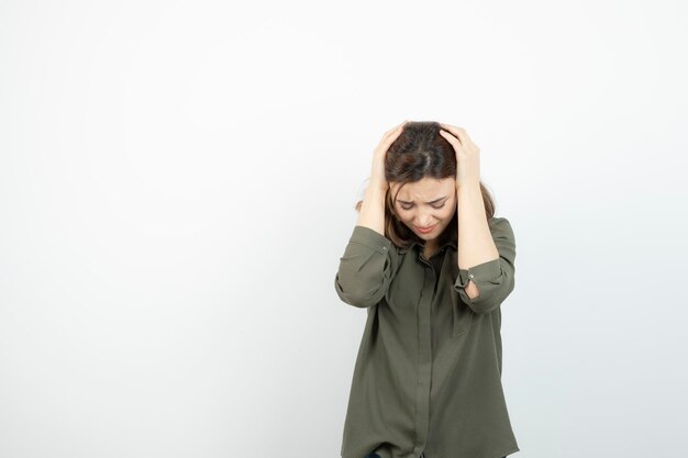 Photo d'une jeune fille ayant des maux de tête sur un mur blanc. Photo de haute qualité