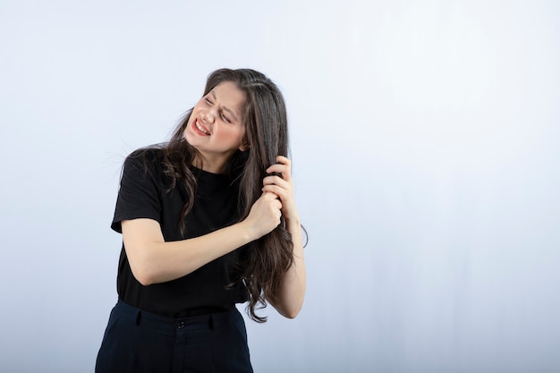 Photo de jeune fille brune tenant ses cheveux gris.