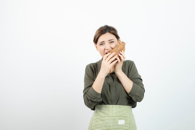 Photo de jeune fille essayant de manger de la noix de coco poilue sur blanc. Photo de haute qualité