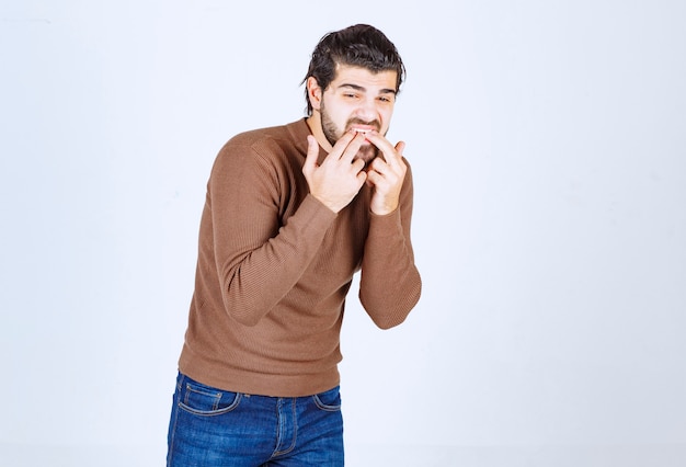 Photo d'un jeune homme essayant de siffler sur un mur blanc. photo de haute qualité