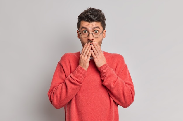 Photo d'un jeune homme européen étonné garde les mains sur la bouche regarde choqué la caméra réagit à une révélation inattendue