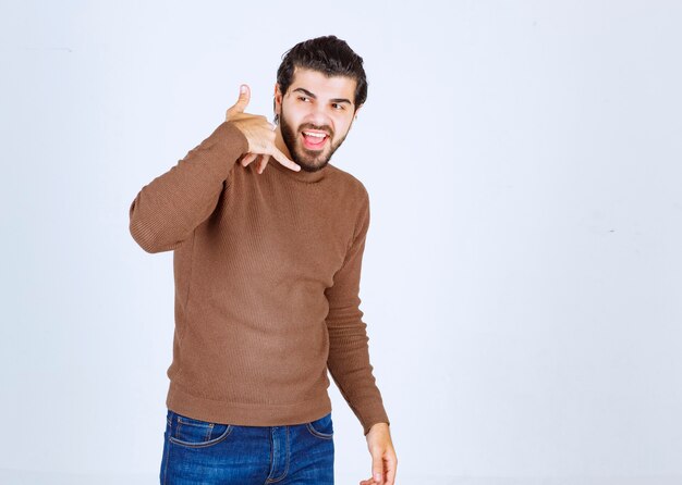 Photo d'un jeune homme souriant debout et montrant un indicatif d'appel. photo de haute qualité