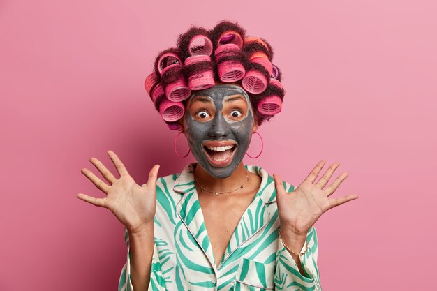 Photo de jeune mannequin femme positive lève les paumes et regarde avec plaisir la caméra