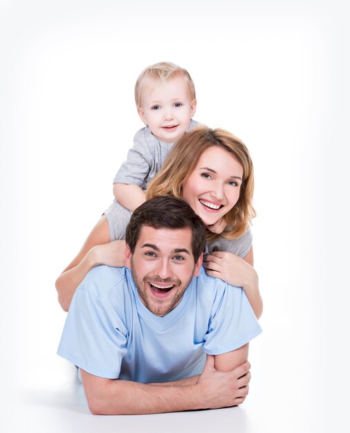 Photo des jeunes parents souriants avec petit enfant allongé sur le sol - isolé