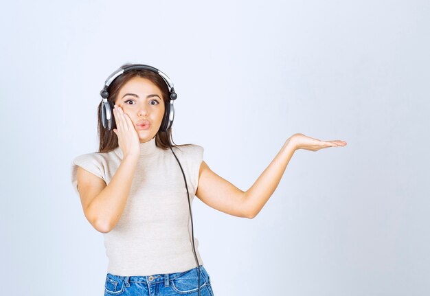 Photo d'une jolie femme modèle écoutant de la musique dans des écouteurs et montrant la main.