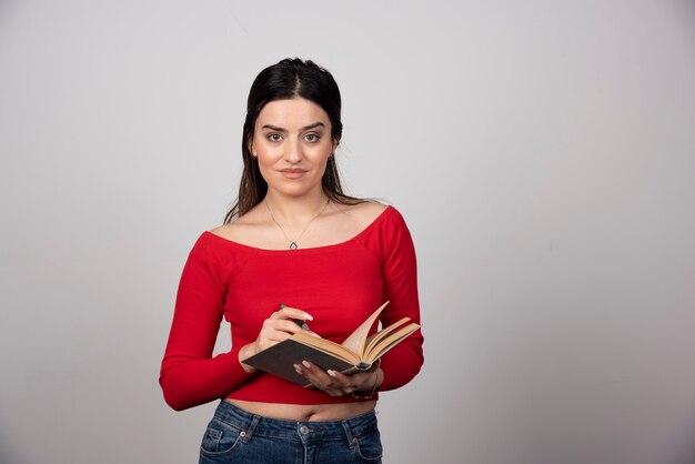 Photo d'une jolie femme tenant un livre ouvert avec un crayon.