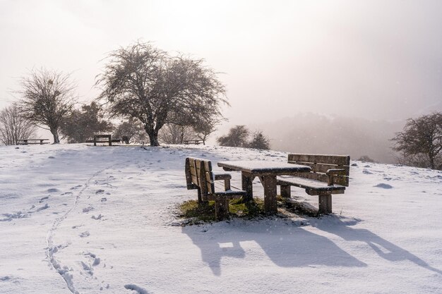 Photo lumineuse d'une aire de pique-nique avec des bancs couverts de neige sur le sommet du mont Aizkorri à Gipuzkoa