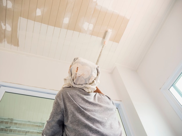 Photo à mise au point partielle d&#39;un homme en train de peindre un plafond à l&#39;aide d&#39;une brosse à rouleau