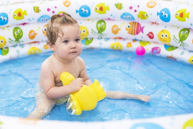 Photo de mise au point peu profonde d'un bébé mignon nageant dans une piscine gonflable