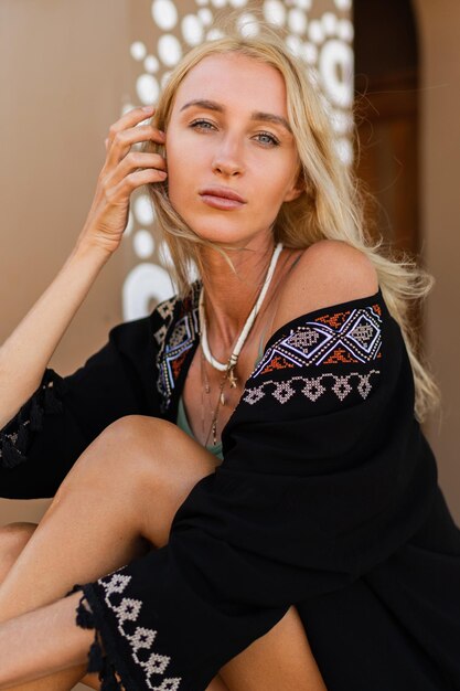 Photo de mode d'une belle femme blonde en tenue d'été bohème posant en plein air. Porter un collier élégant. Ambiance tropicale.