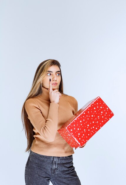 Photo d'un modèle de femme séduisante tenant un cadeau rouge.