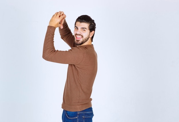 Photo gratuite photo d'un modèle homme brune debout à l'arrière et montrant le cœur avec les mains. photo de haute qualité