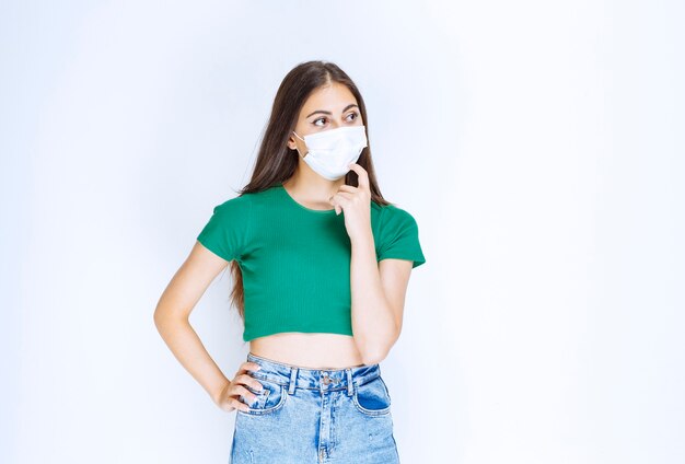 Photo d'un modèle de jeune femme debout et portant un masque médical de protection.