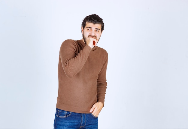 Photo d'un modèle de jeune homme effrayé debout et se mordant le poing. photo de haute qualité