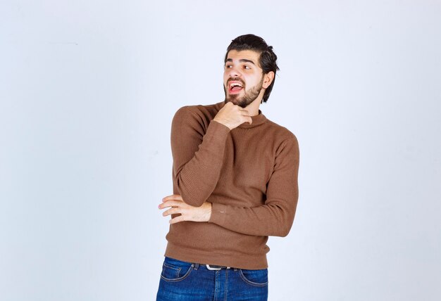 Photo d'un modèle de jeune homme séduisant debout et posant sur un mur blanc. photo de haute qualité