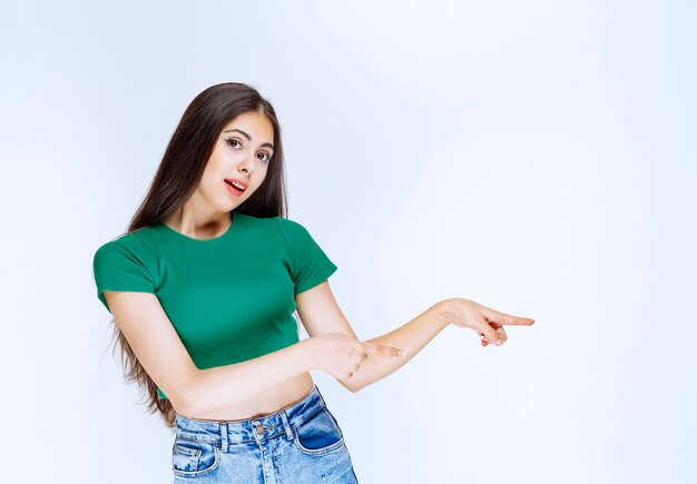 Photo d'un modèle de jolie fille avec la bouche ouverte debout et pointant de côté.