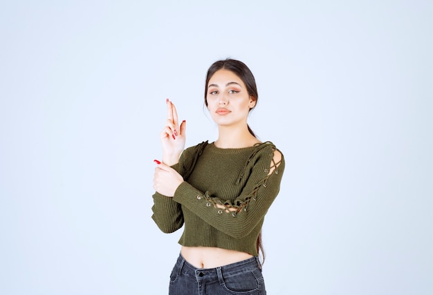 Photo d'un modèle sérieux de jeune femme faisant un pistolet avec la main et les doigts.
