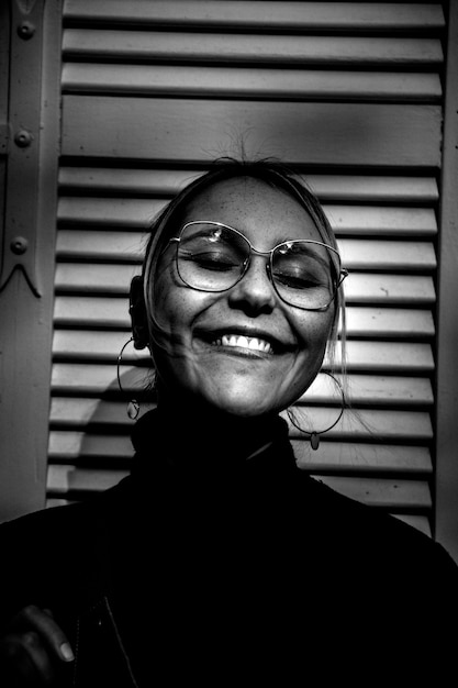 Photo en niveaux de gris d'une femme souriante portant un haut à col roulé