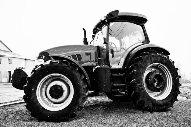 Photo en noir et blanc d'un tracteur par temps de neige