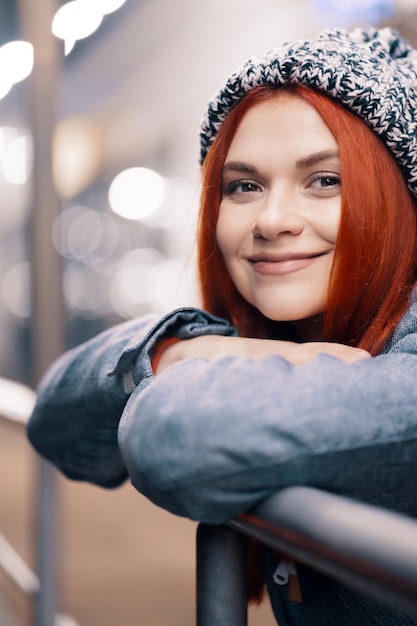 Photo gratuite photo de nuit en plein air d'une jeune belle fille souriante heureuse bénéficiant d'une décoration festive, dans la rue de la ville européenne, portant un bonnet tricoté