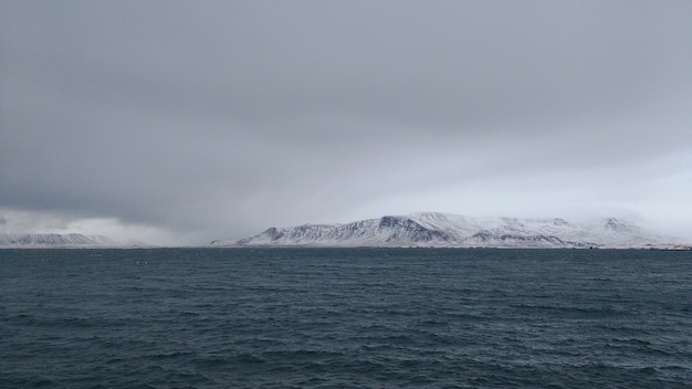 Photo panoramique d'une côte de montagne couverte de neige par temps nuageux