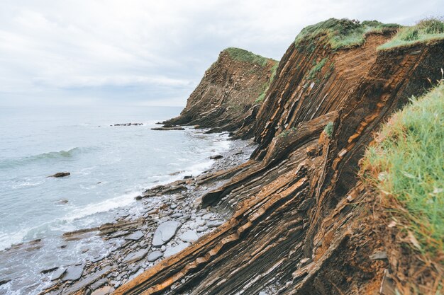 Photo panoramique de falaises remplies d'herbe verte à côté de la mer bleue pendant la journée