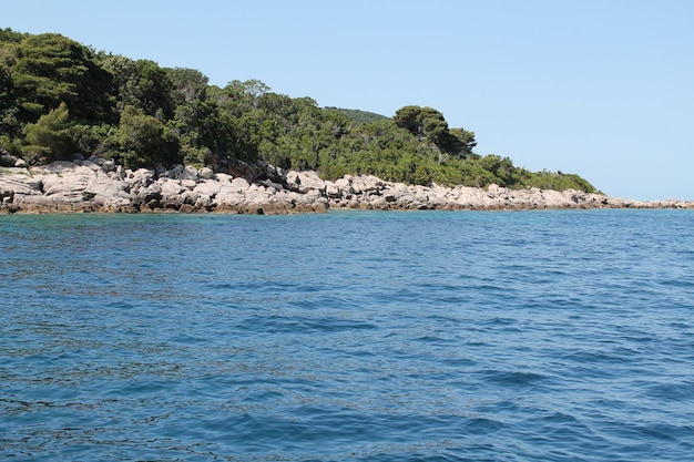 Photo de paysage d'une colline verte dans l'eau bleue avec un ciel bleu clair