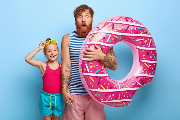 Photo gratuite photo de père et fille au gingembre stupéfaits posant dans des tenues de piscine