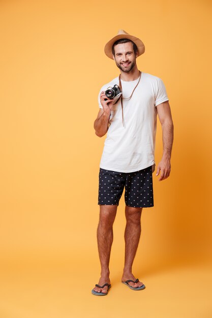 Photo pleine longueur d'un homme avec un appareil photo rétro dans les mains