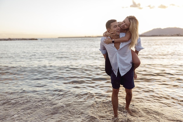 Photo pleine longueur d'un joli couple s'amusant ensemble sur la plage