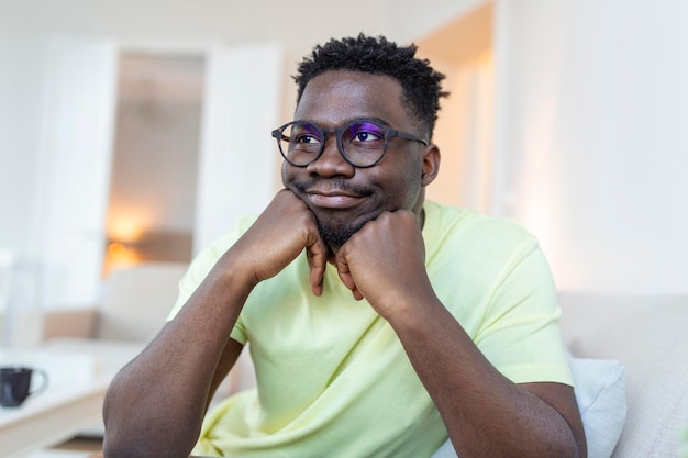 Photo gratuite photo de profil d'un jeune homme afro-américain souriant à lunettes pose dans son propre appartement
