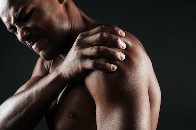 Photo recadrée de jeune homme afro-américain torse nu avec douleur à l'épaule