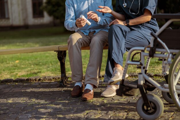 Photo recadrée d'un patient âgé en convalescence ayant une conversation avec une infirmière assise ensemble