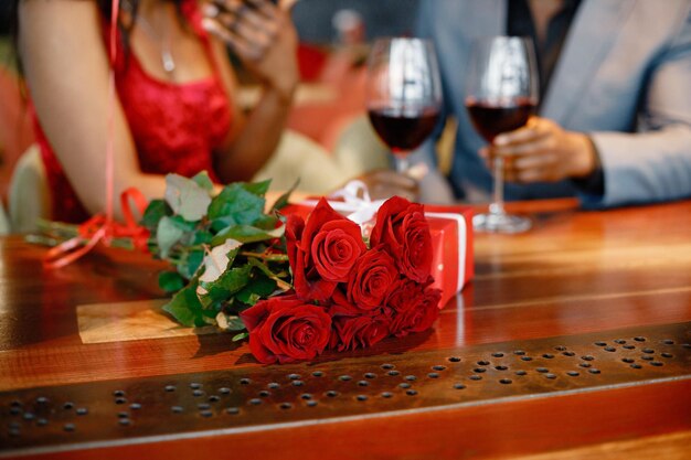 Photo recadrée d'une rose rouge et d'une boîte cadeau sur une table au restaurant