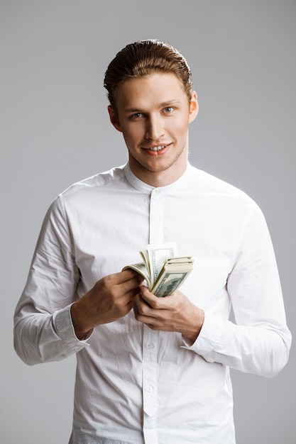 Photo de séduisant homme de race blanche avec de l'argent dans les mains