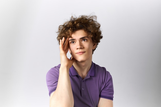 Photo de Studio d'un beau mec rêveur se souvenant de moments agréables, regardant vers le haut, tenant la main sur sa tête.