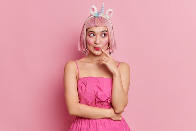 Photo de Studio de belle femme réfléchie aux cheveux roses regarde de côté