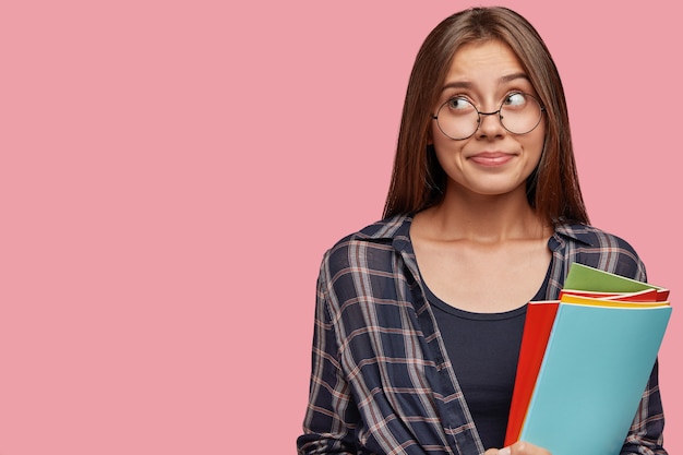 Photo gratuite photo de studio de belle jeune femme d'affaires posant contre le mur rose avec des lunettes