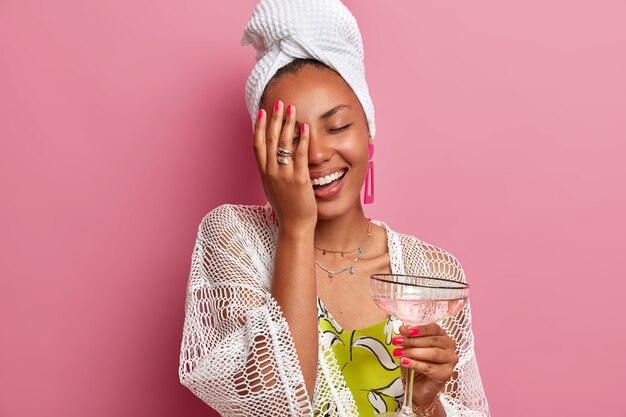 Photo de Studio de femme heureuse à la peau sombre fait sourire paume le visage garde largement les yeux fermés