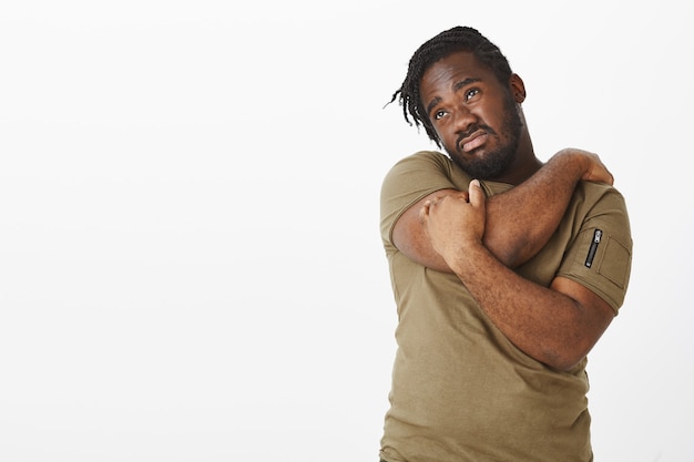 Photo gratuite photo de studio de gars déçu dans un t-shirt marron posant contre le mur blanc