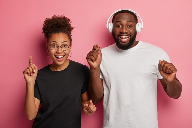 Photo de Studio d'heureux homme et femme noire dansant au rythme de la musique