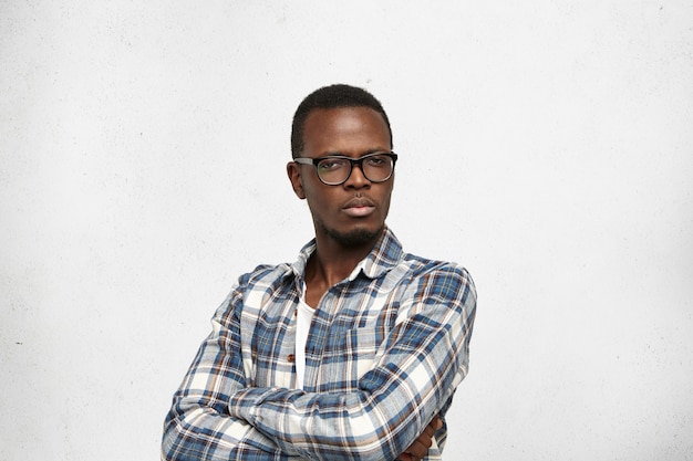 Photo gratuite photo de studio de jeune homme africain suspect sceptique debout au mur blanc