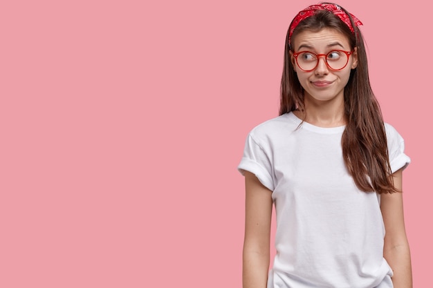 Photo de Studio de jolie jeune femme concentrée de côté avec une expression curieuse, a les cheveux longs