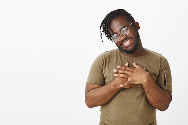 Photo de Studio de mec insouciant avec des lunettes posant contre le mur blanc