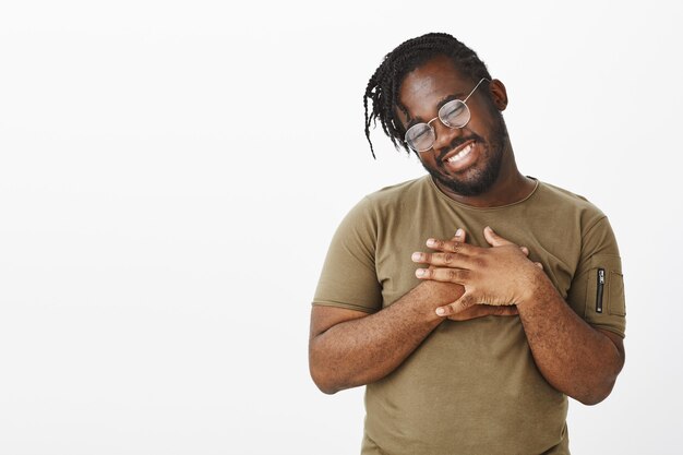 Photo de Studio de mec insouciant avec des lunettes posant contre le mur blanc