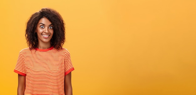 Photo gratuite une photo de taille d'une femme afro-américaine charmante, étonnée et excitée, avec des cheveux bouclés et des yeux éclatants.