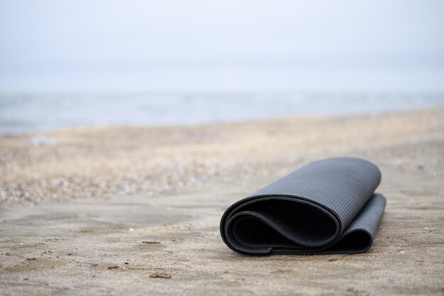 Photo d'un tapis de yoga roulé à la plage Photo de haute qualité