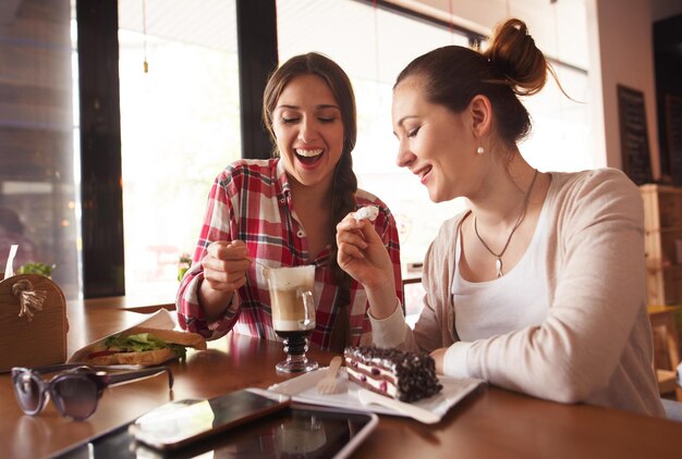 Photo tonique de dames regardant une tasse de café au lait souriant et passant leurs week-ends au café ou au restaurant