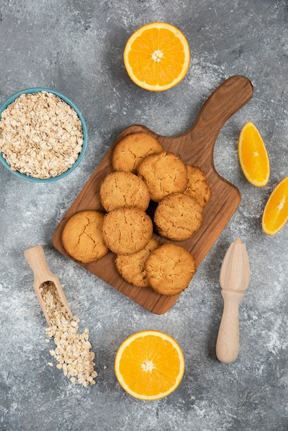 Photo verticale de biscuits faits maison avec de la farine d'avoine et des tranches d'orange sur une table grise.